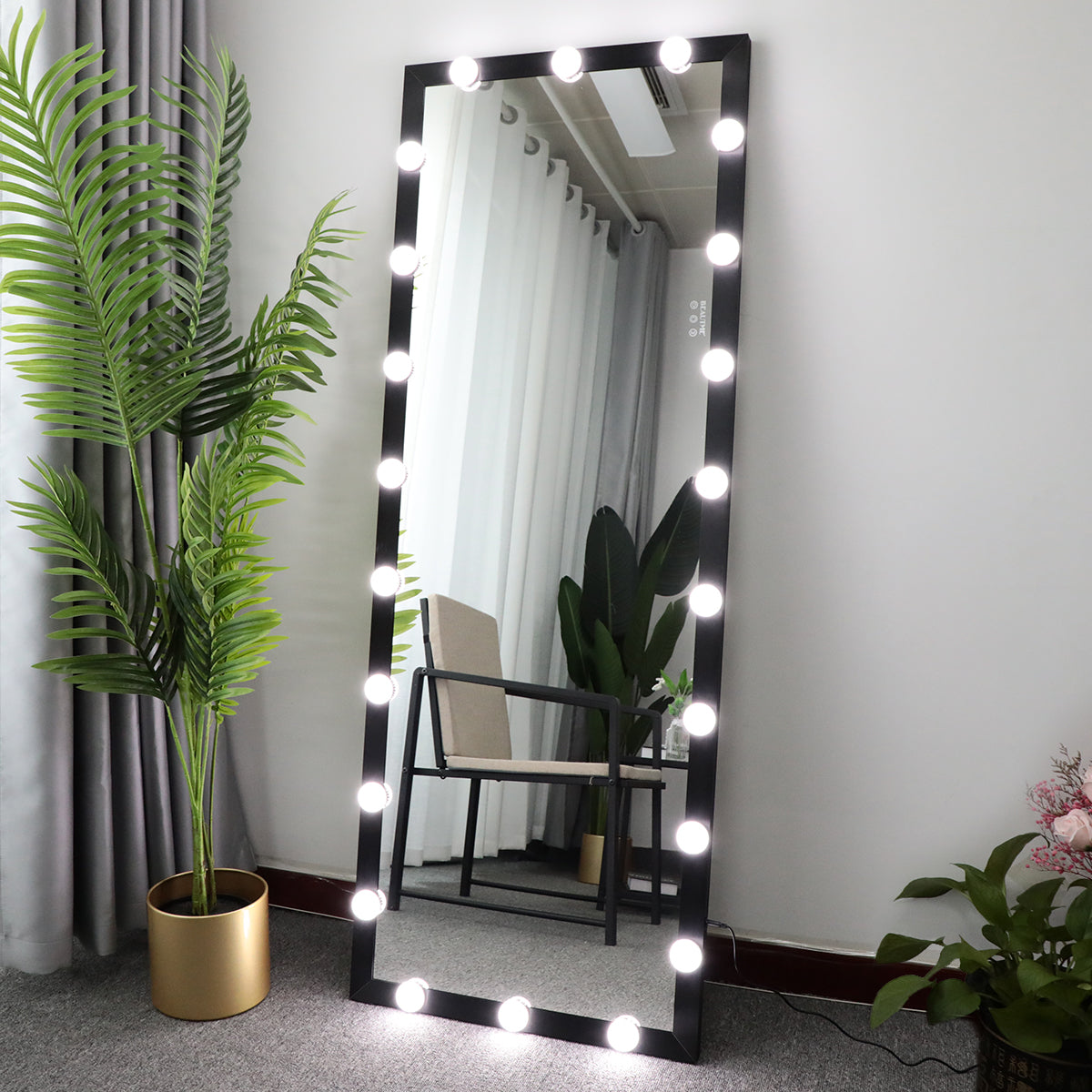 Large floor mirror with LED lights in a room with plants and furniture.